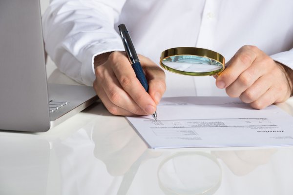 hombre con una lupa y un documento contable agencia detectives
